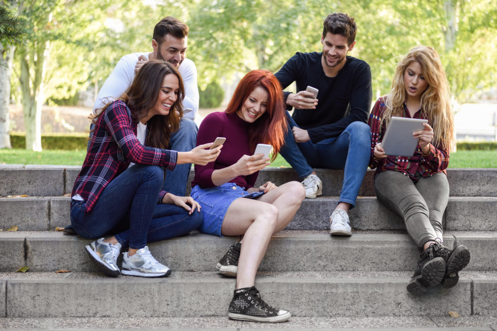 bir grup genç oturmuş cep telefonu, tablet ve bilgisayarlarından App Store'da yer alan uygulamalara oy veriyor ve yorum yapıyorlar. 